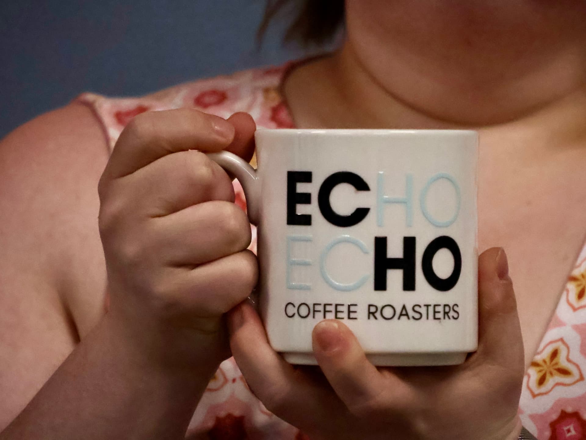 Someone holding a warm ECHO Coffee Roasters mug