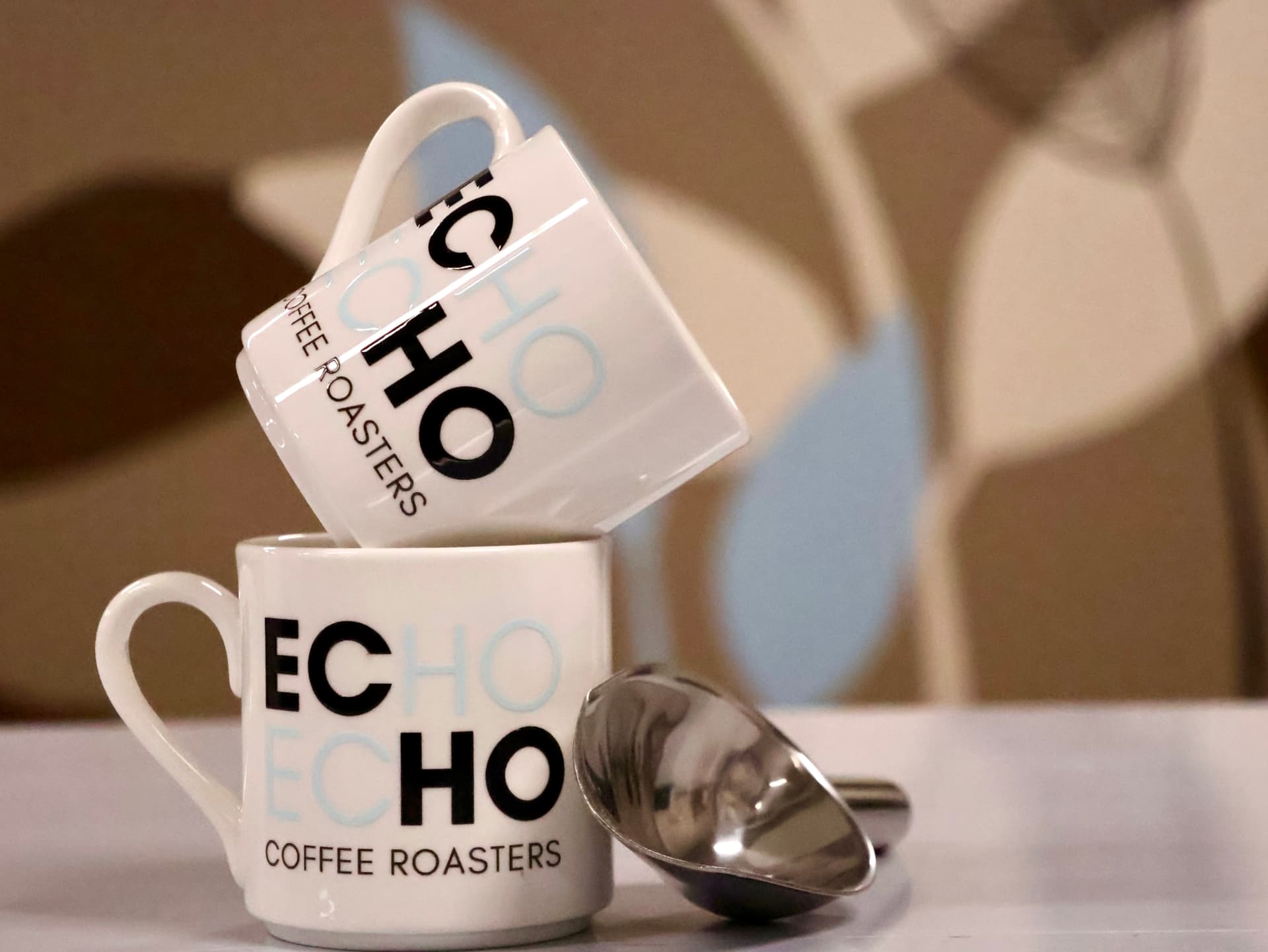 Stacked ECHO Coffee Roasters mugs with a scoop